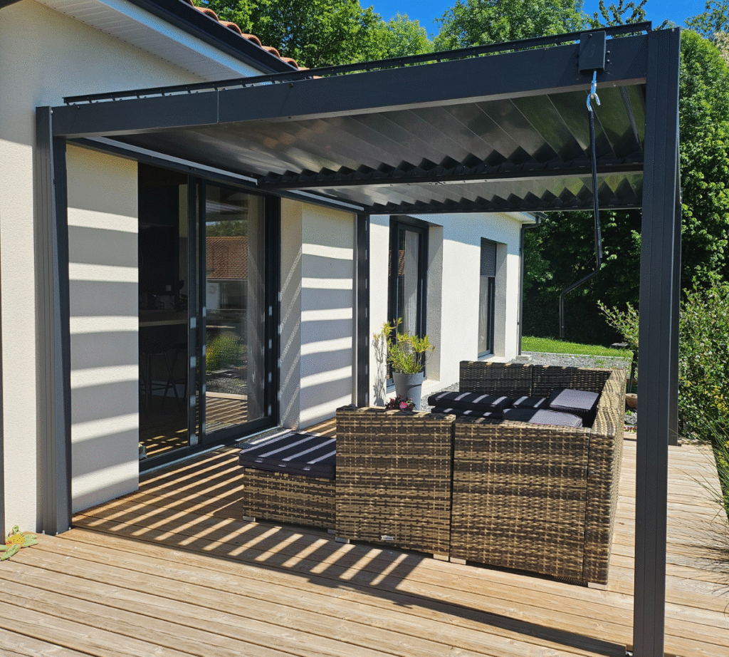 Profitez d’un espace extérieur moderne sublimé par une pergola bioclimatique en aluminium, véritable pièce maîtresse de cette terrasse. Sa structure élégante et contemporaine offre une protection optimale contre le soleil tout en laissant filtrer une lumière naturelle grâce à ses lames orientables. Cette pergola crée un jeu d’ombres raffiné sur le sol en bois, apportant fraîcheur et confort à tout moment de la journée. Idéale pour aménager un coin détente ou recevoir des invités, elle valorise l’esthétique de la maison tout en s’intégrant harmonieusement à l’environnement verdoyant. La pergola devient ici un atout incontournable pour profiter pleinement de la terrasse, quelle que soit la saison