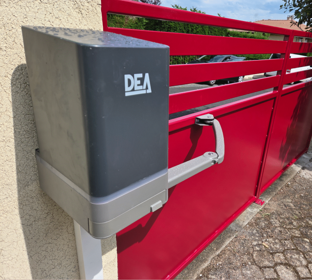 Zoom sur l'installation d'un moteur DEA, solution de motorisation haut de gamme pour portails battants. Ce modèle robuste et silencieux est idéal pour automatiser l'ouverture d’un portail en aluminium, comme celui présenté ici dans une teinte bordeaux éclatante. Fixé solidement au mur, le bloc moteur DEA est associé à un bras articulé discret qui garantit un mouvement fluide et sécurisé à chaque ouverture. Ce système allie fiabilité, design compact et performance, même en usage intensif. Un choix parfait pour ceux qui souhaitent conjuguer confort d’utilisation, sécurité et esthétique moderne.
